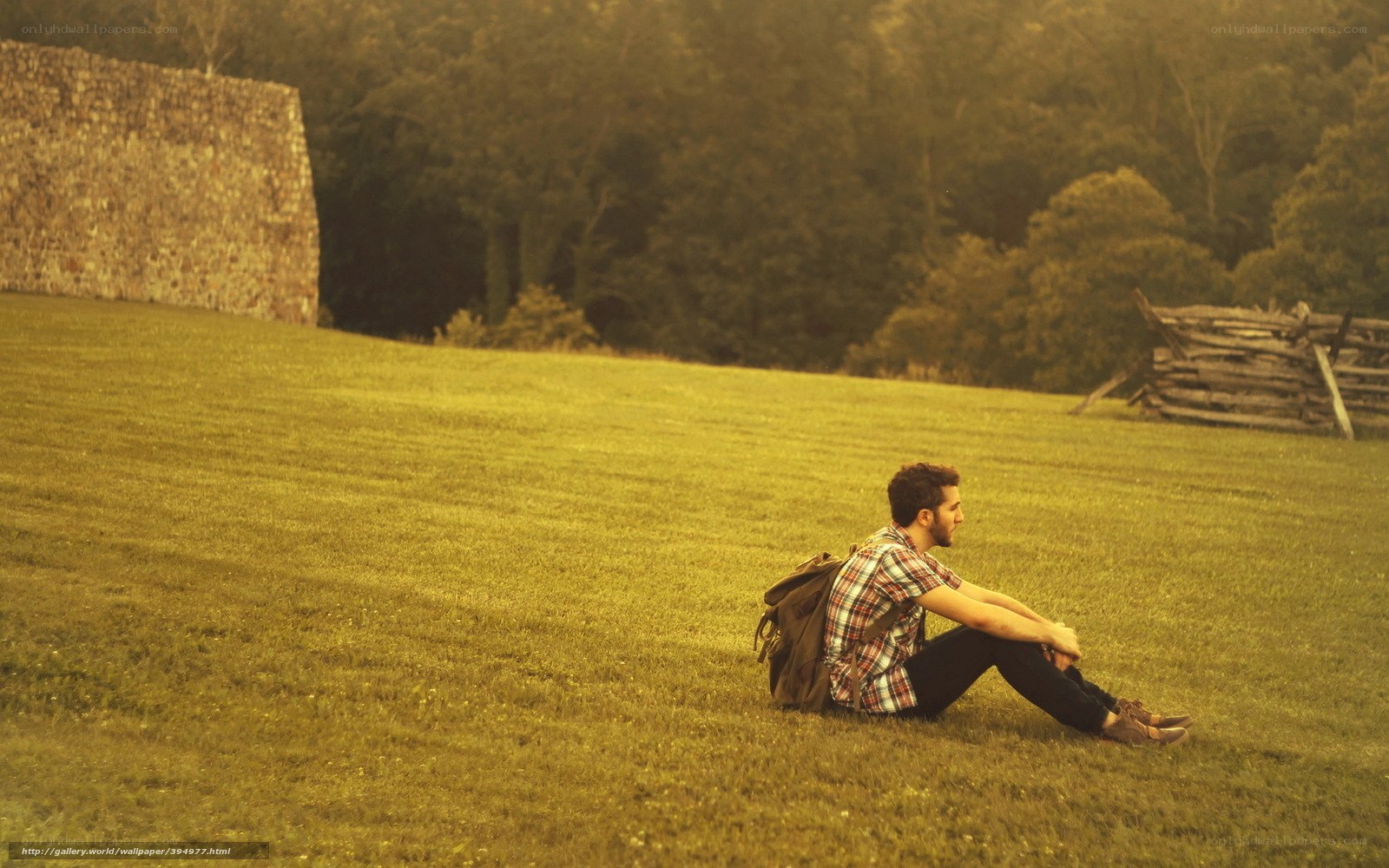 man sitting on grass with backpack