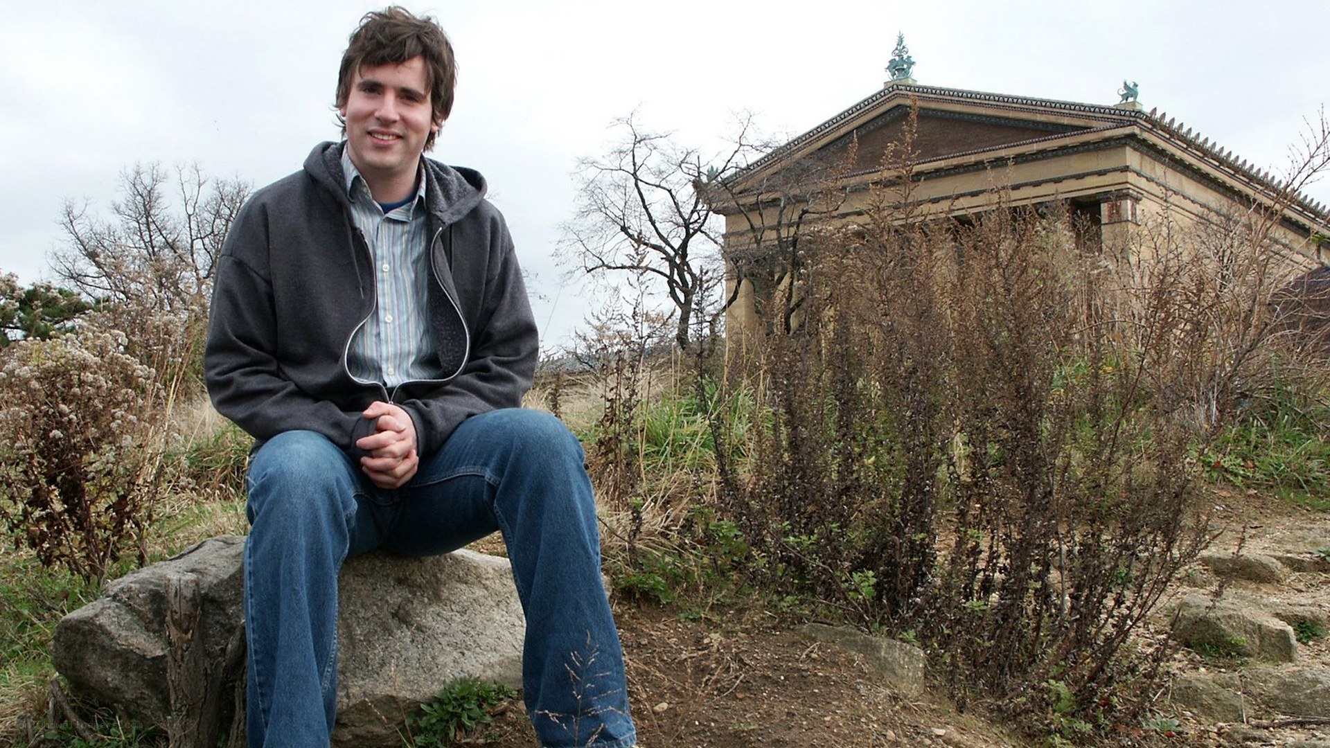 man sitting on rock near temple