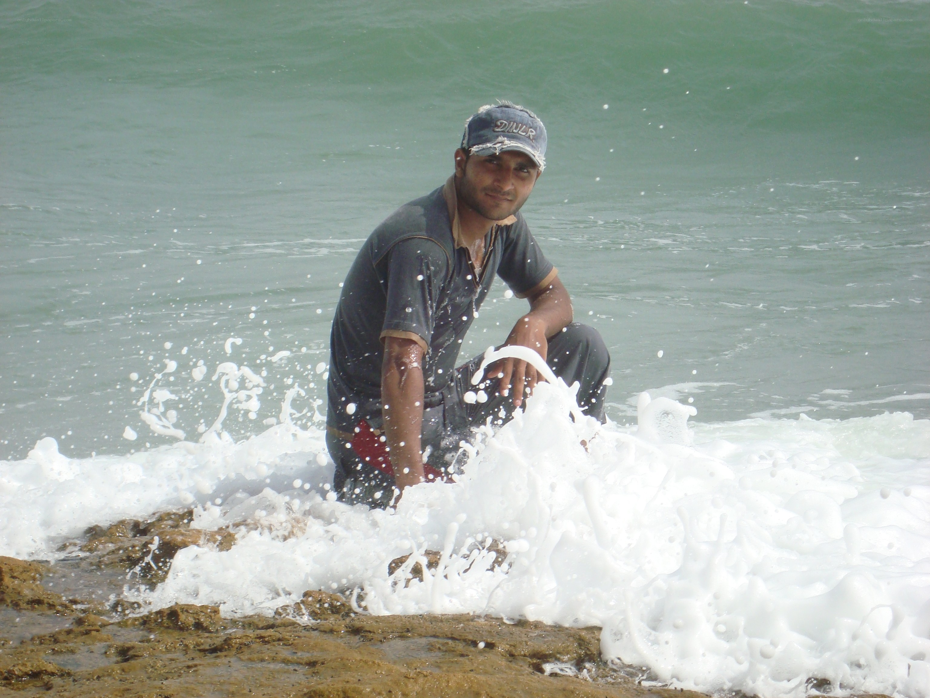 man sitting on rocks at beach