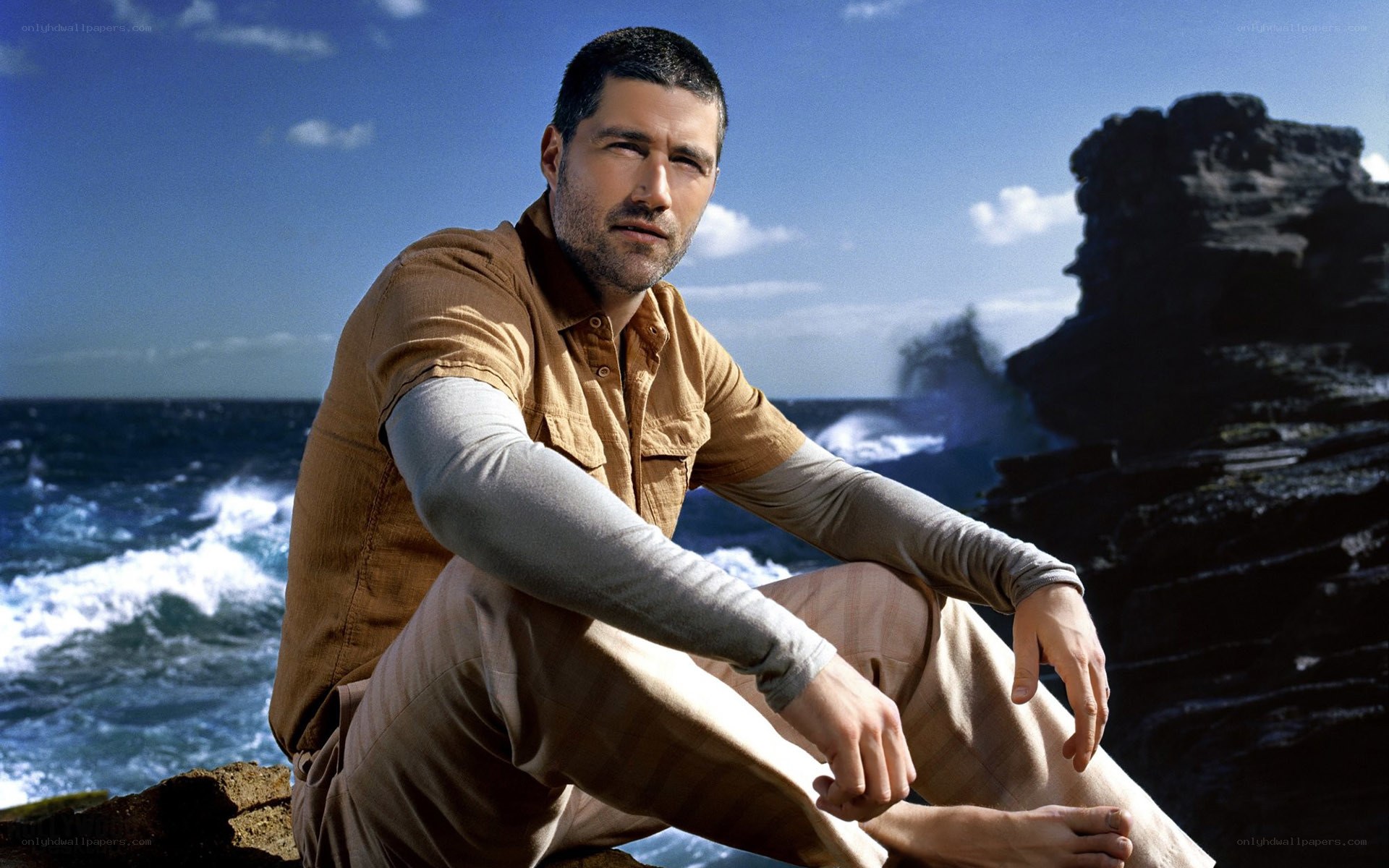 man sitting on rocky shore