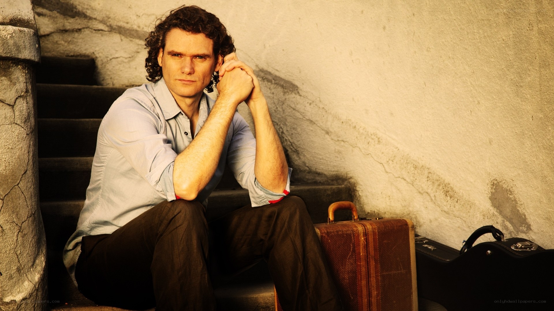 man sitting on stairs with suitcase