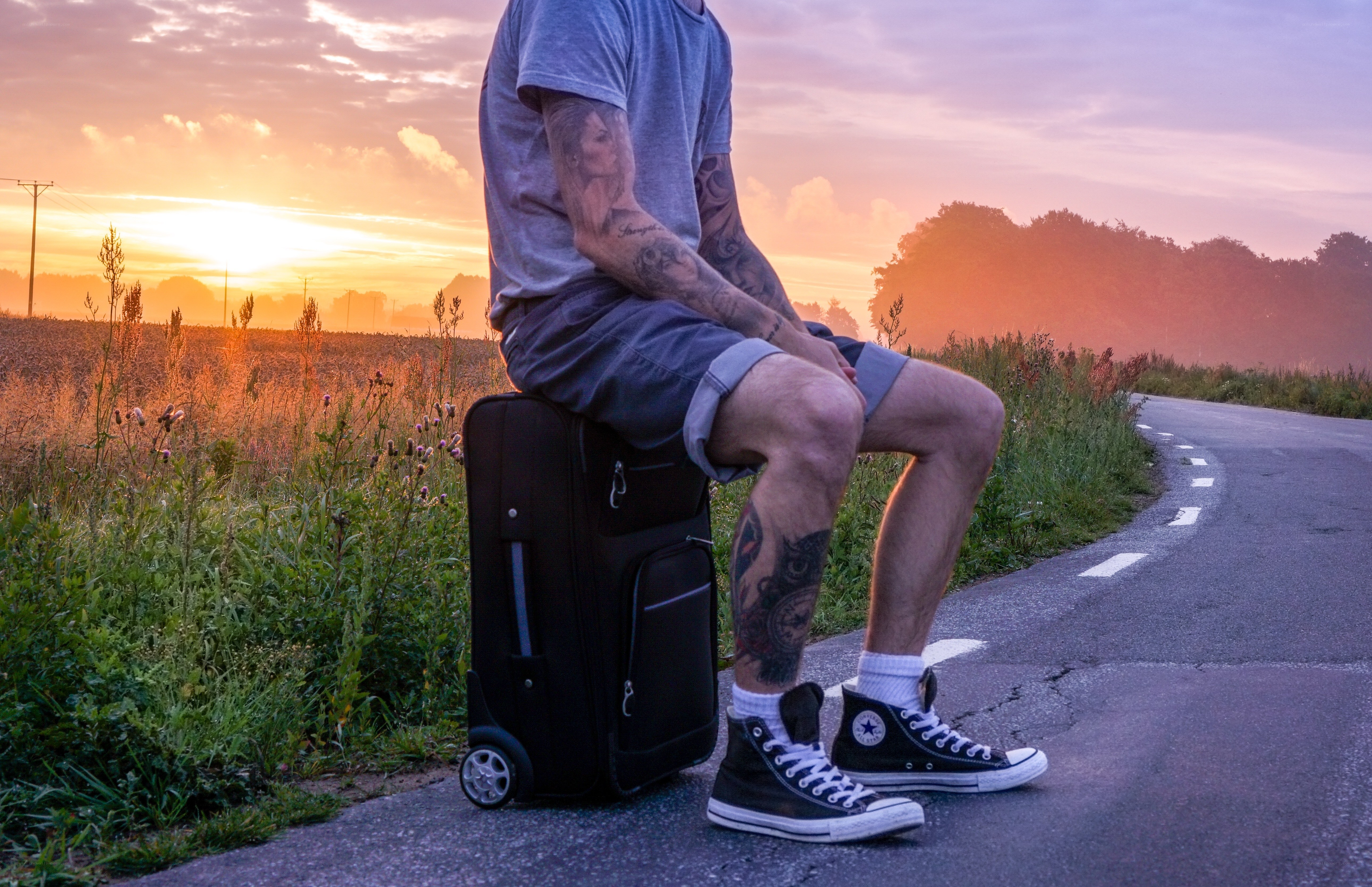 Man sitting on suitcase at sunset