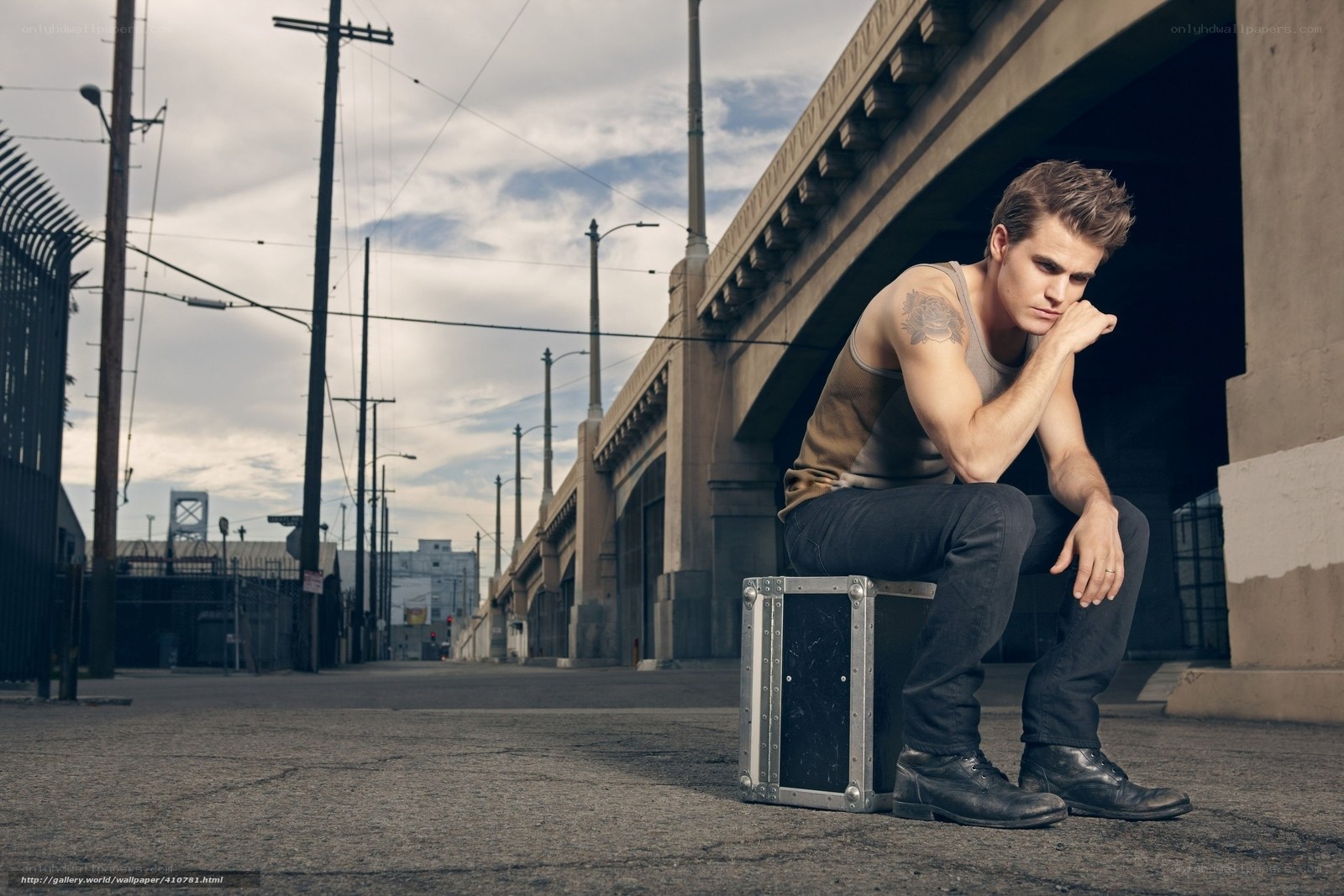 man sitting under a bridge
