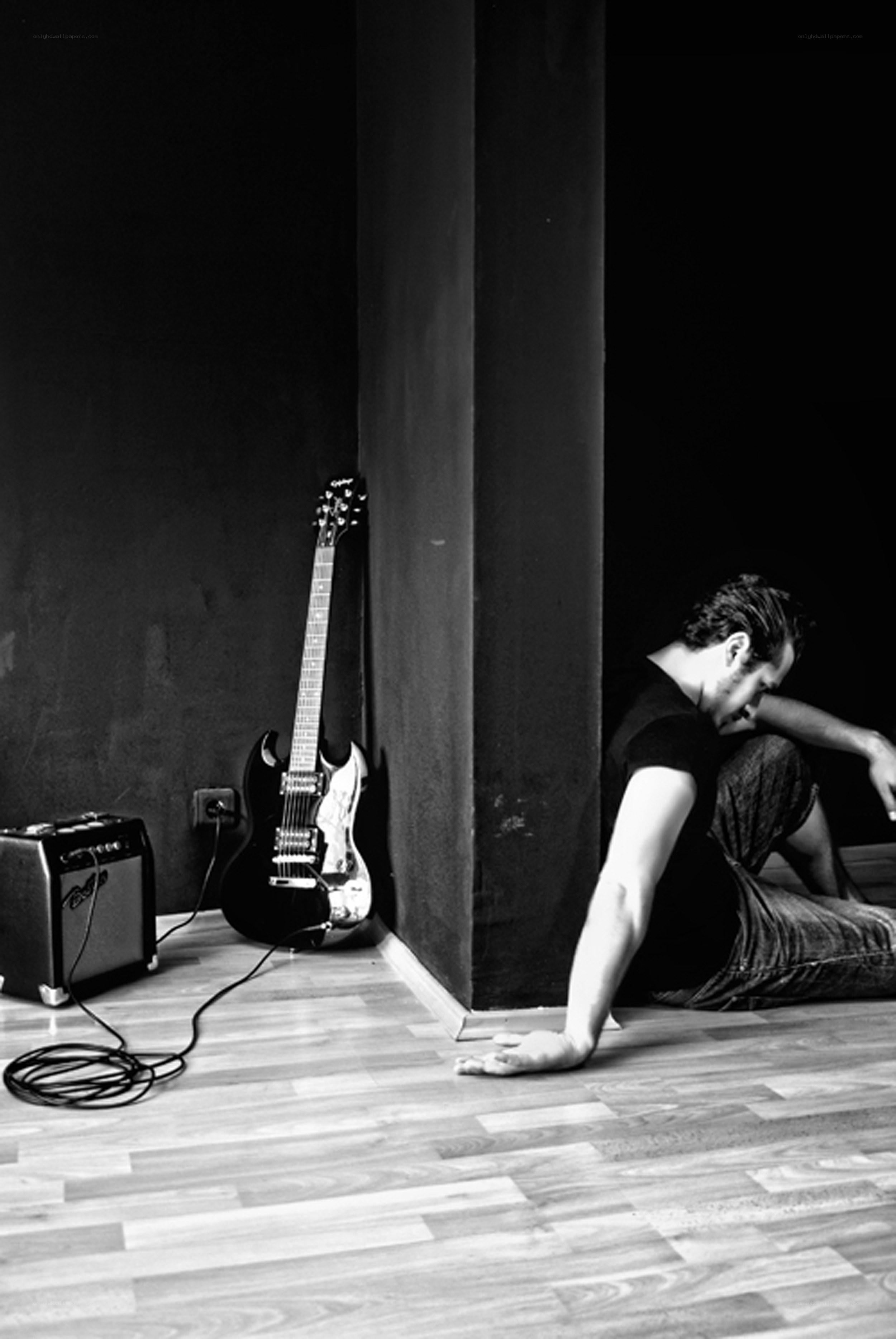 Man sitting with guitar in corner