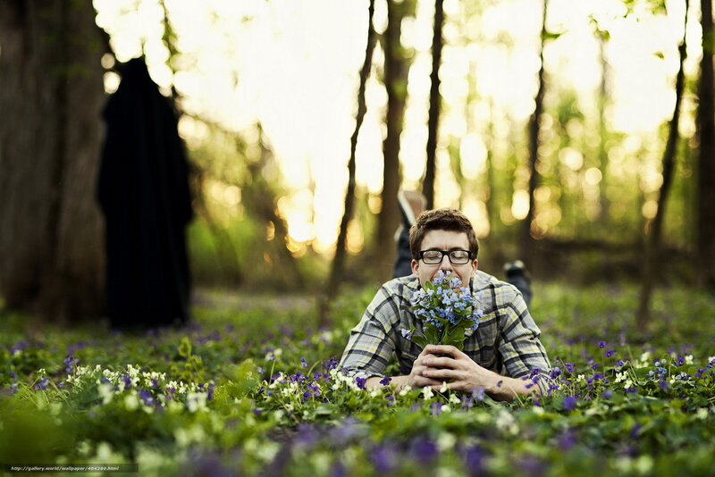 Man smelling flowers in forest