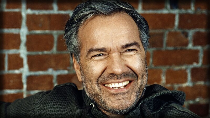 man smiling in front of brick wall