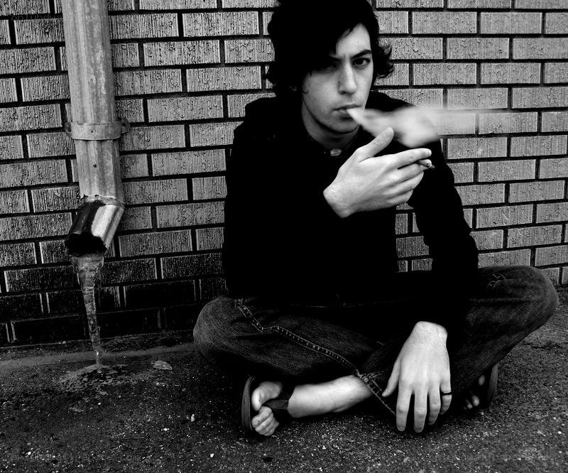 man smoking against brick wall