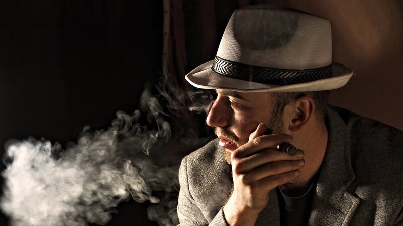 man smoking cigar in hat