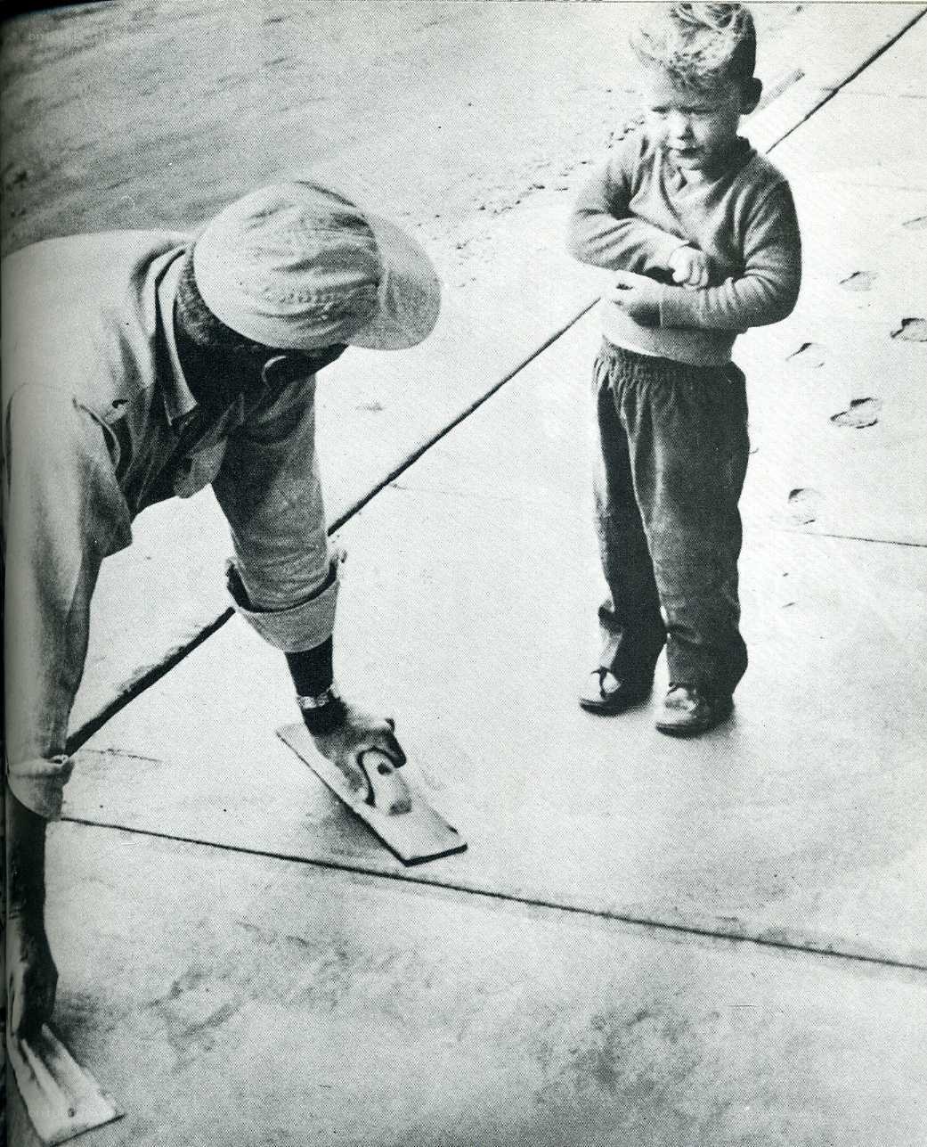 Man smoothing concrete with child watching