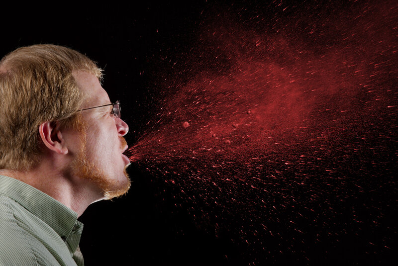 man spitting red powder