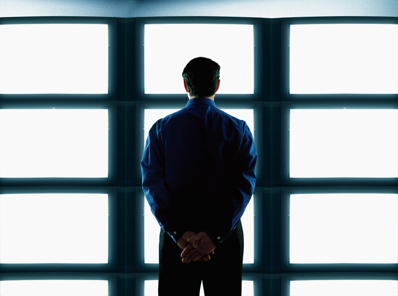 Man standing before bright screens