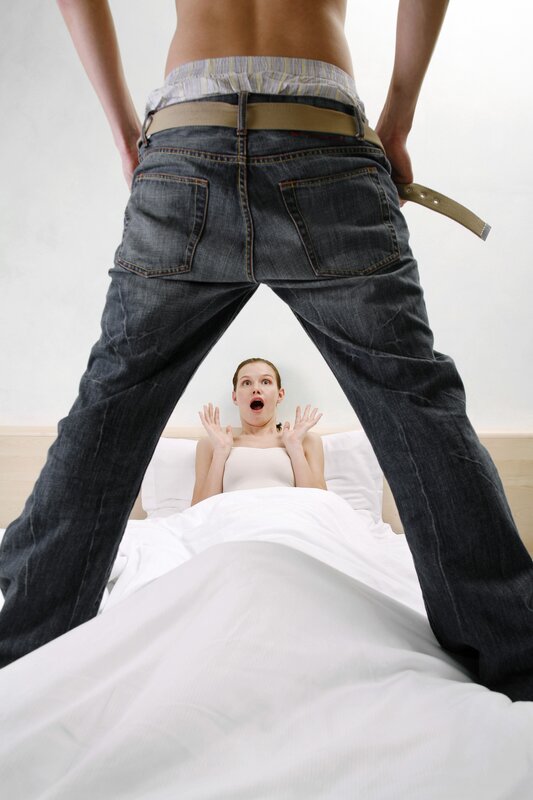 Man standing over woman in bed