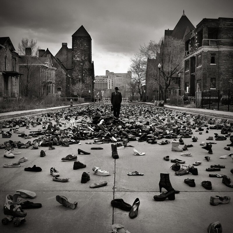 Man stands amidst scattered shoes
