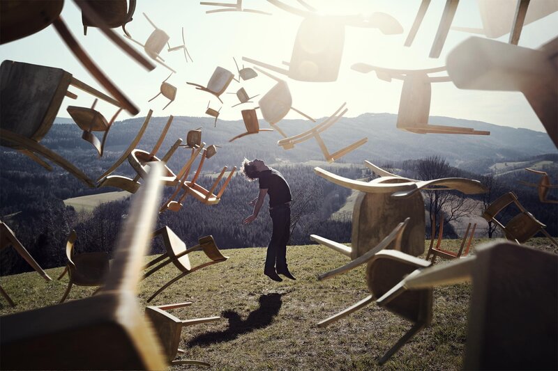 Man Surrounded by Chairs