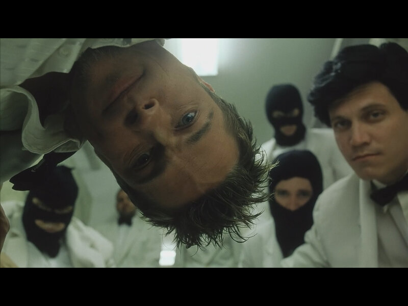 Man surrounded by masked figures