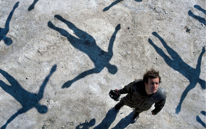 man surrounded by shadow figures