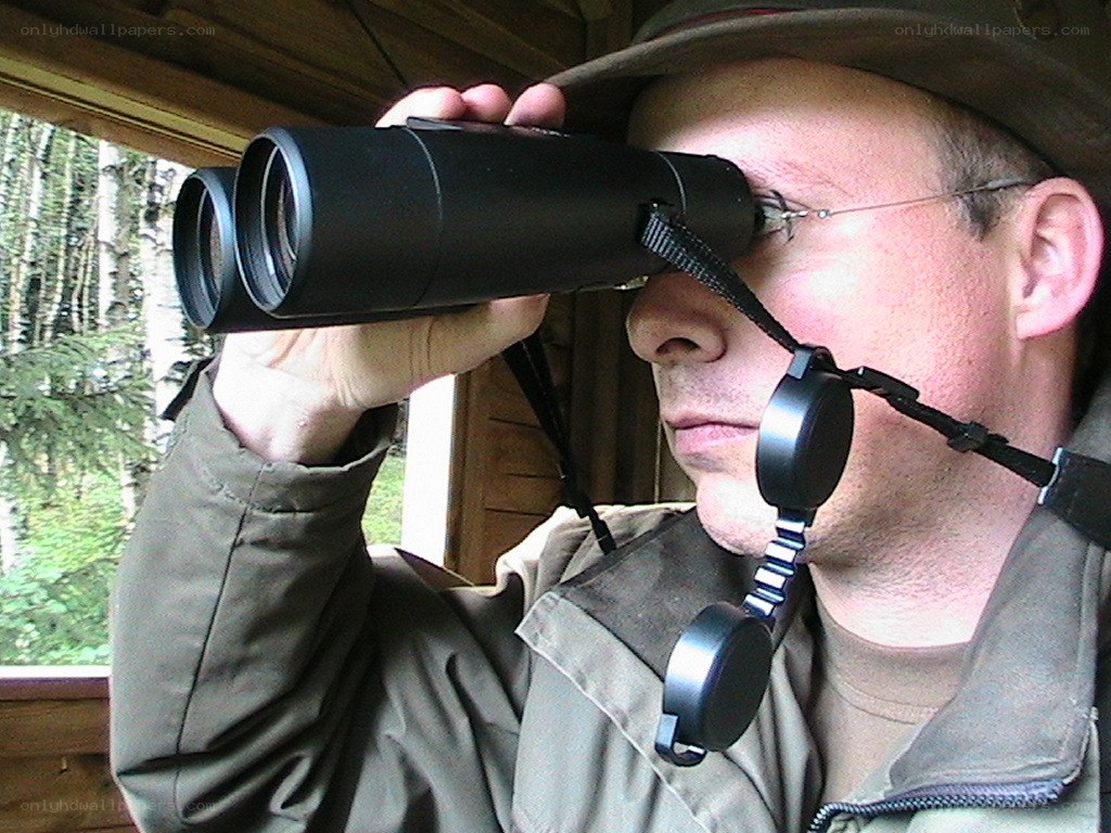 man using binoculars in forest