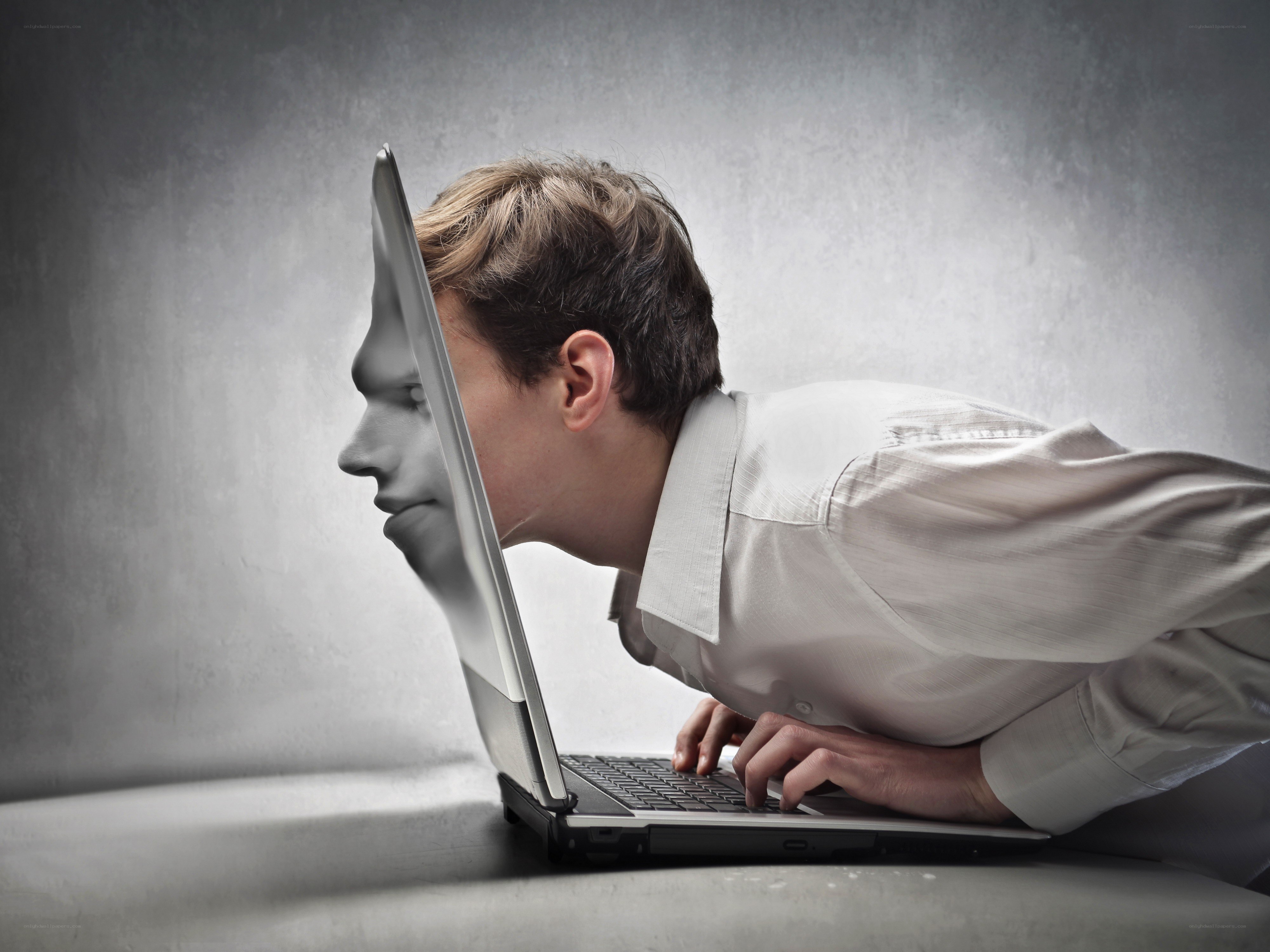 man using laptop with face on screen