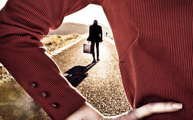 Man walking down a road with suitcase