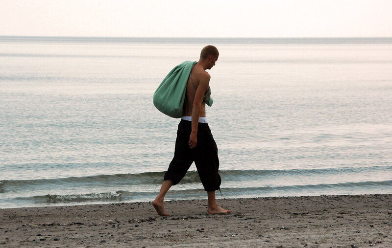 Man walking on beach with bag