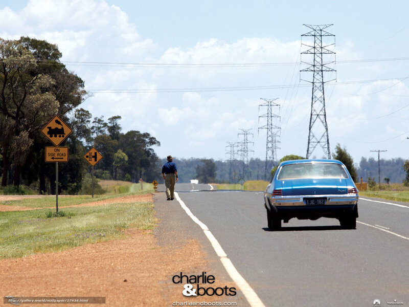 Man walking on road with blue car