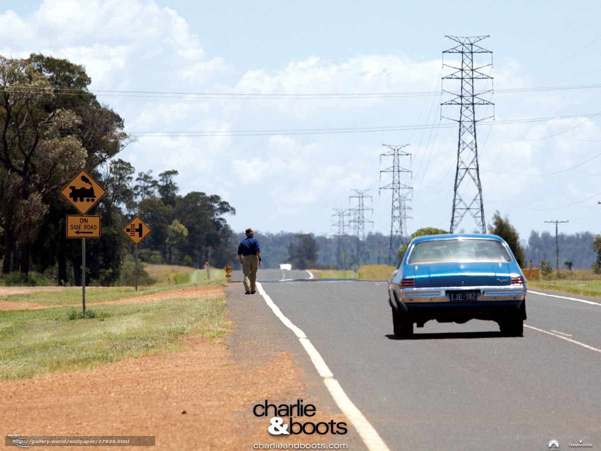 Man walking on road with blue car