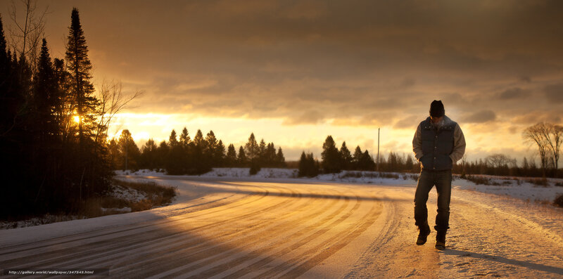 Man walking on snowy road at sunset