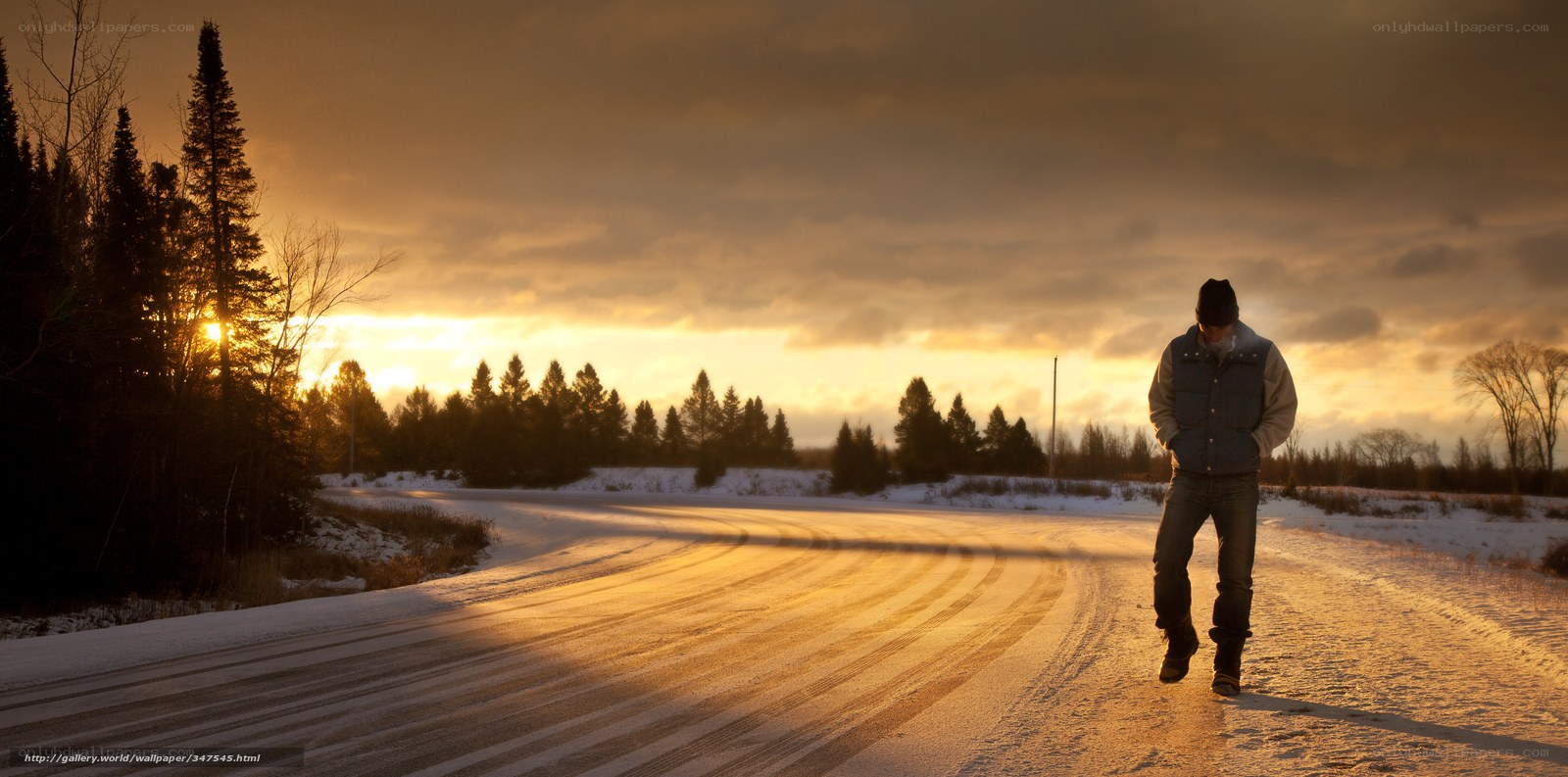 Man walking on snowy road at sunset