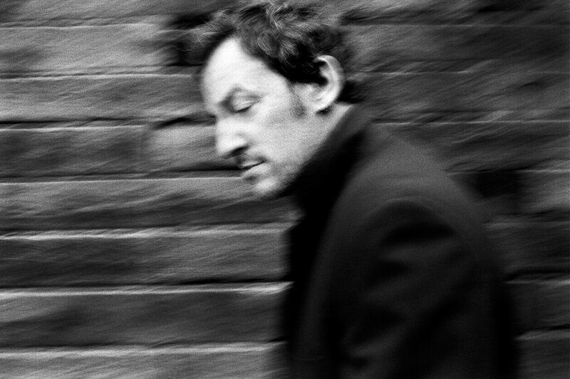 Man walking past brick wall