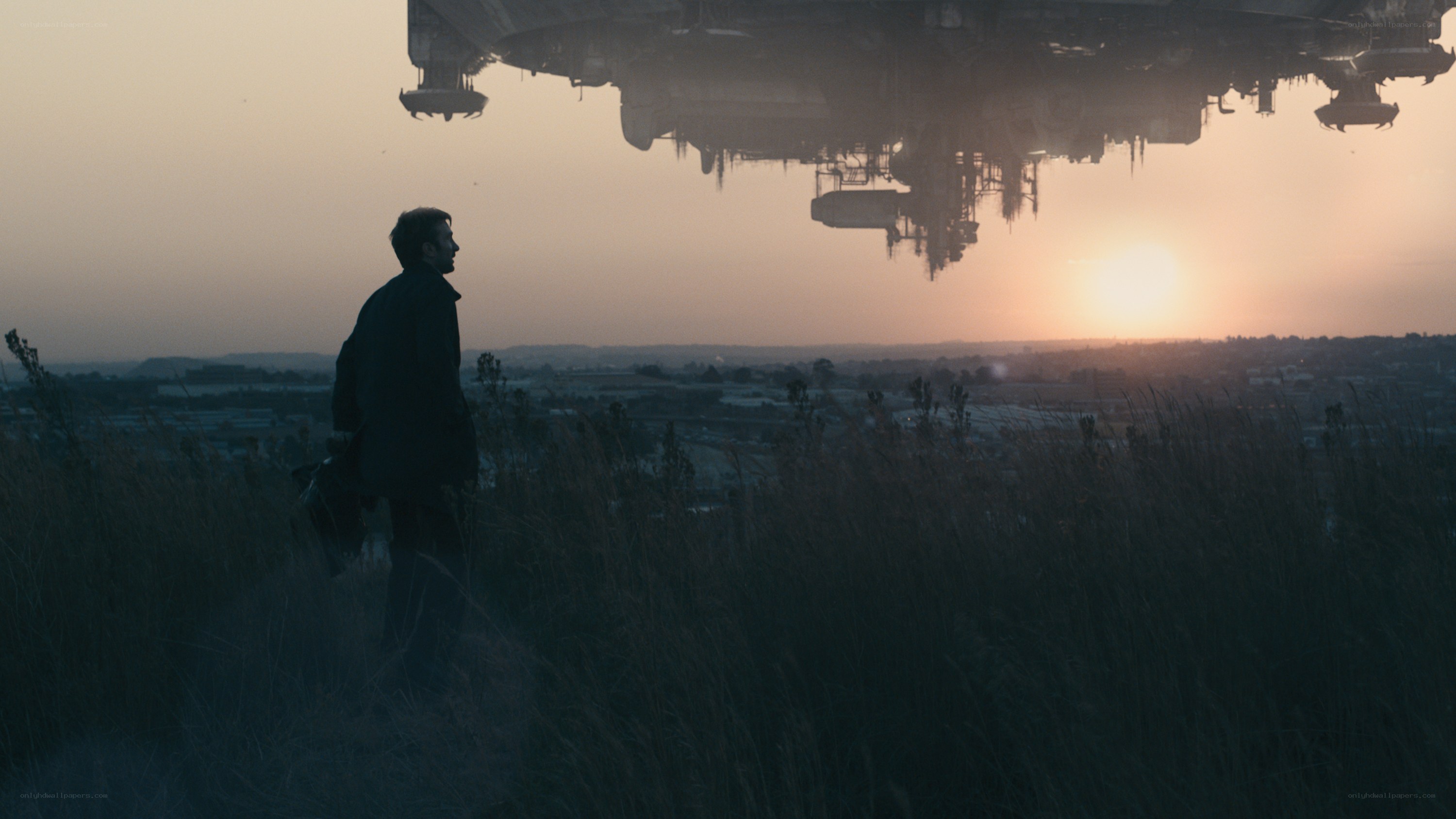 Man watches alien ship at sunset