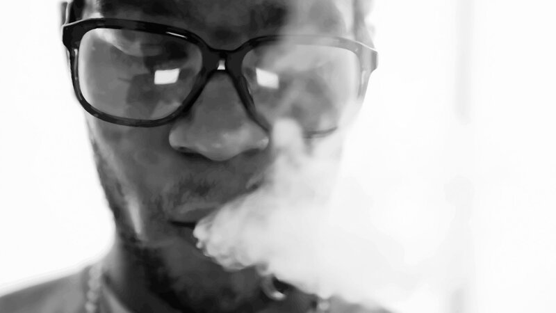 man wearing glasses exhaling smoke
