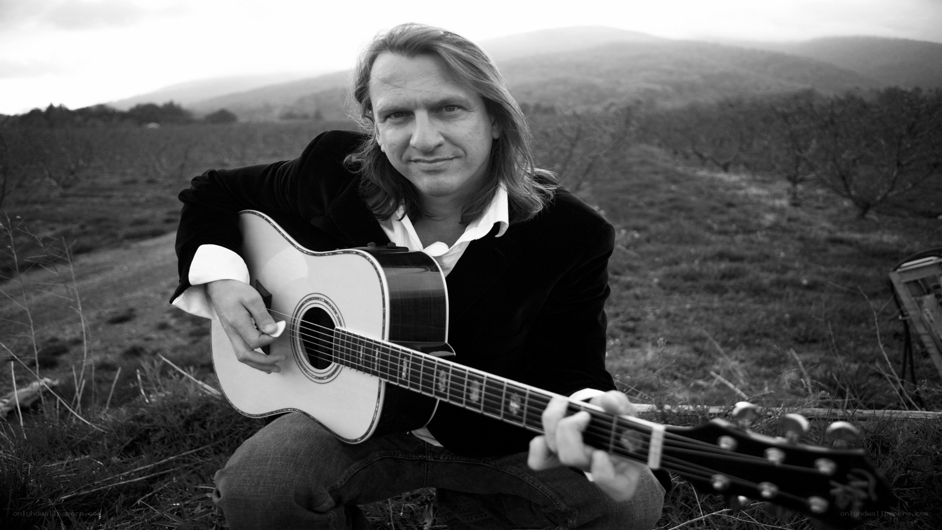 man with acoustic guitar in field