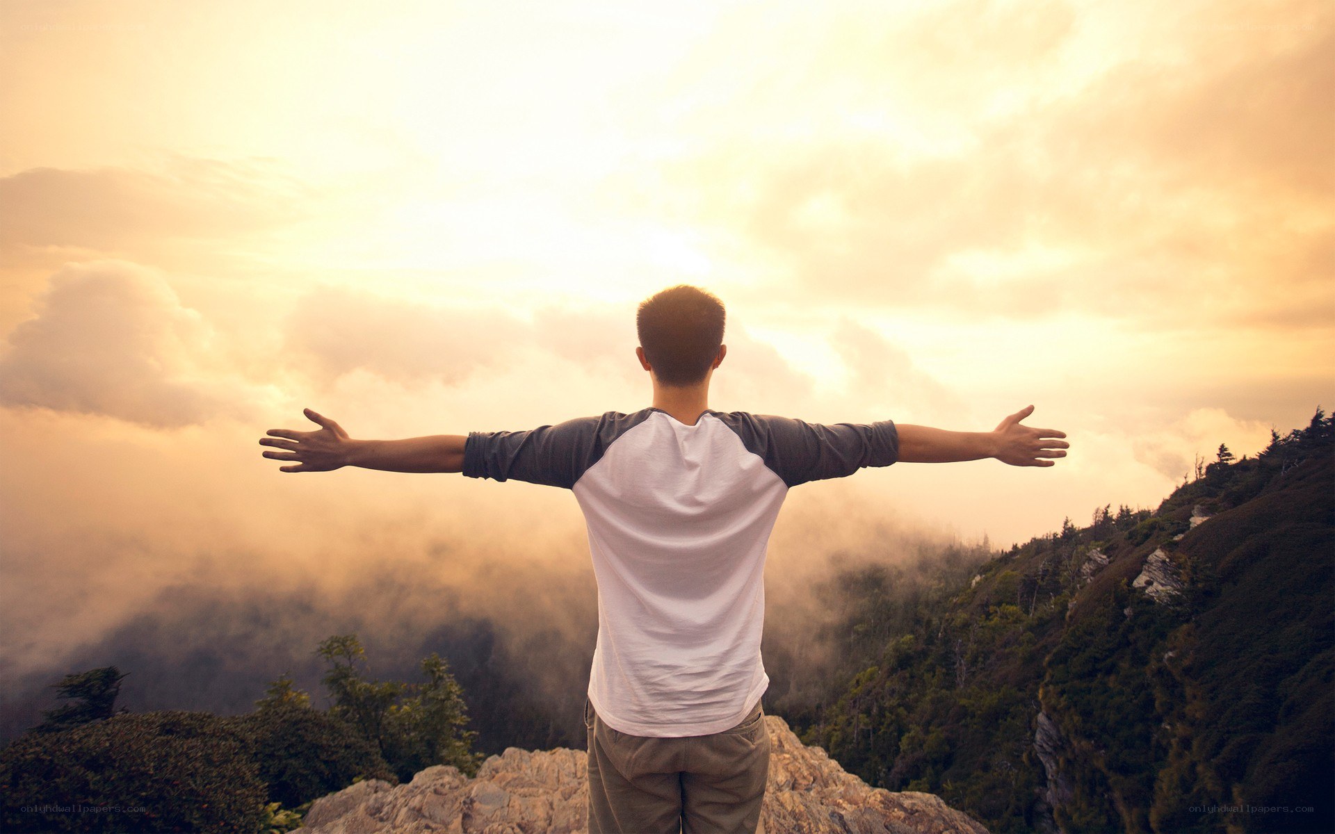 man with arms outstretched at sunset