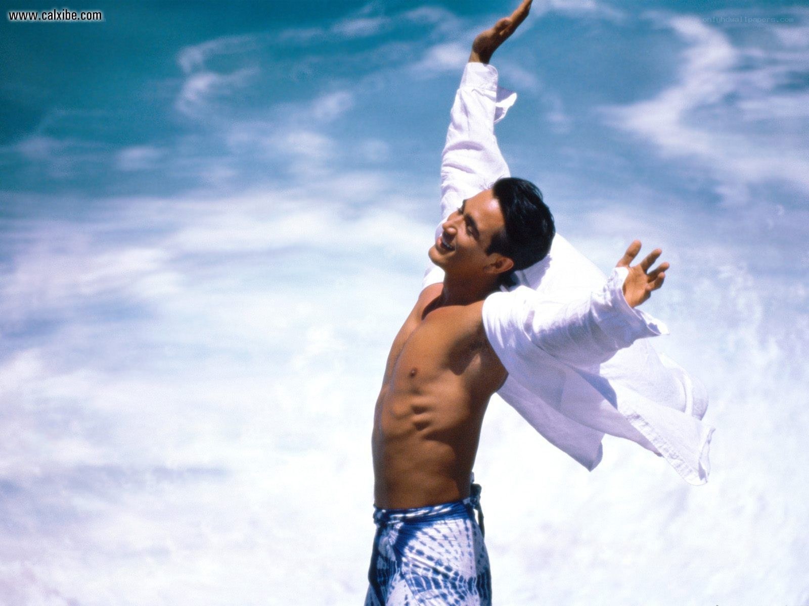 man with arms raised on beach