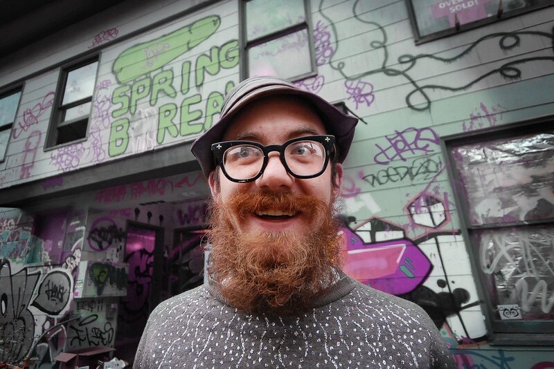 man with beard in front of graffiti wall