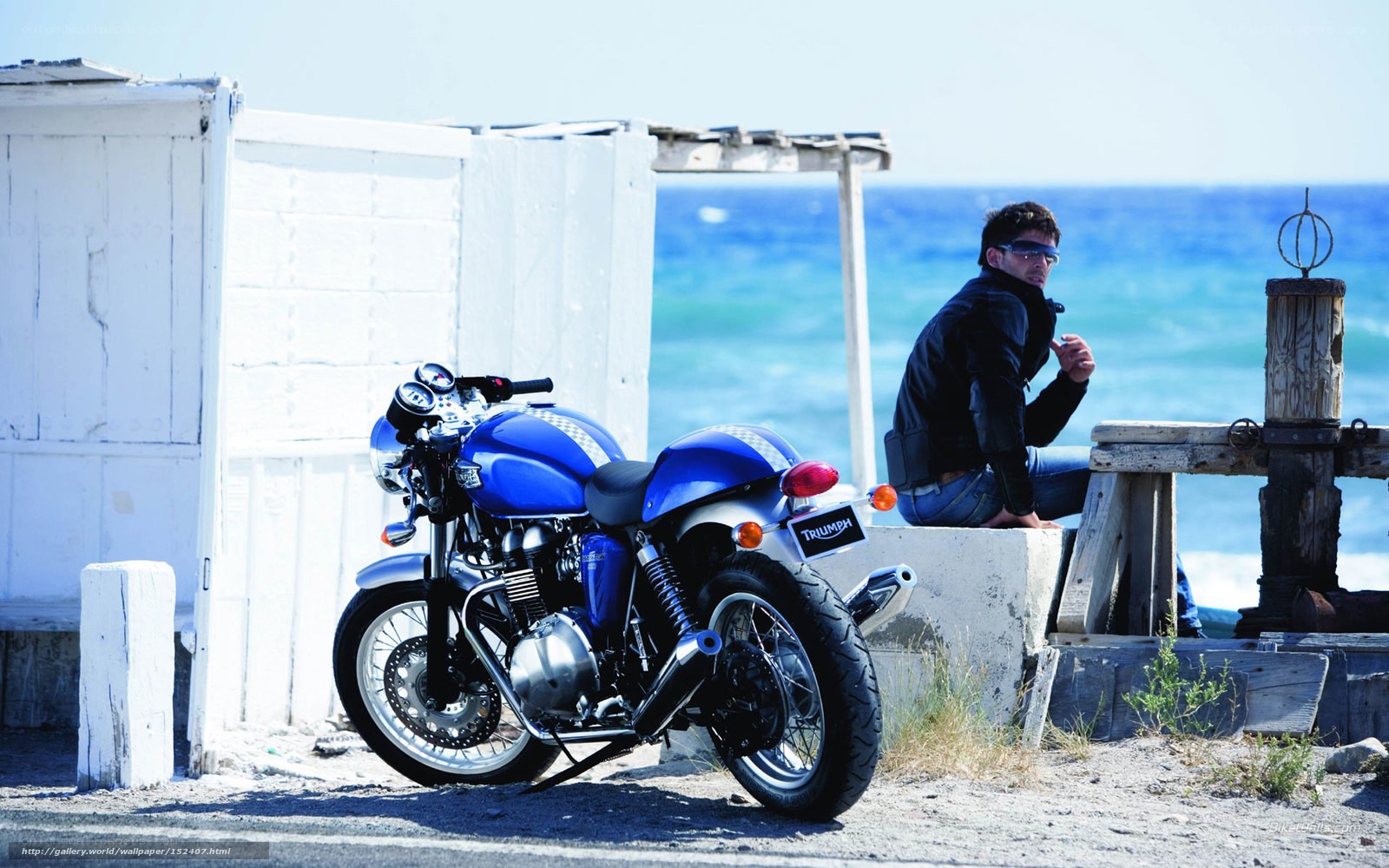 Man with blue motorcycle by the sea