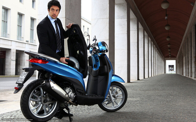 Man with blue scooter in city