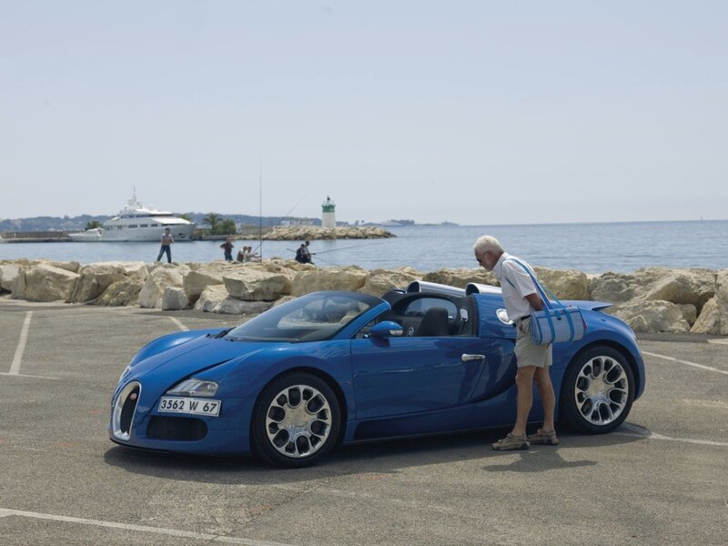 Man with blue sports car by the sea