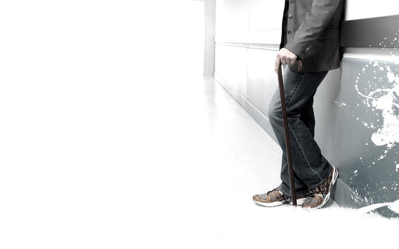 man with cane leaning on wall
