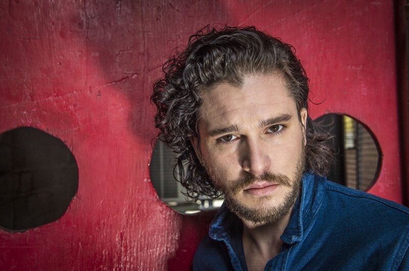 man with curly hair against red wall