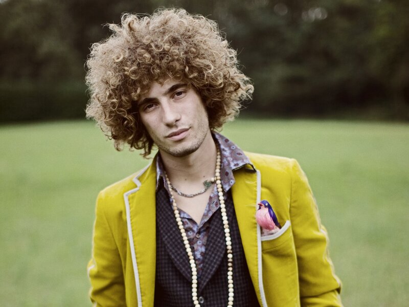 man with curly hair and yellow jacket