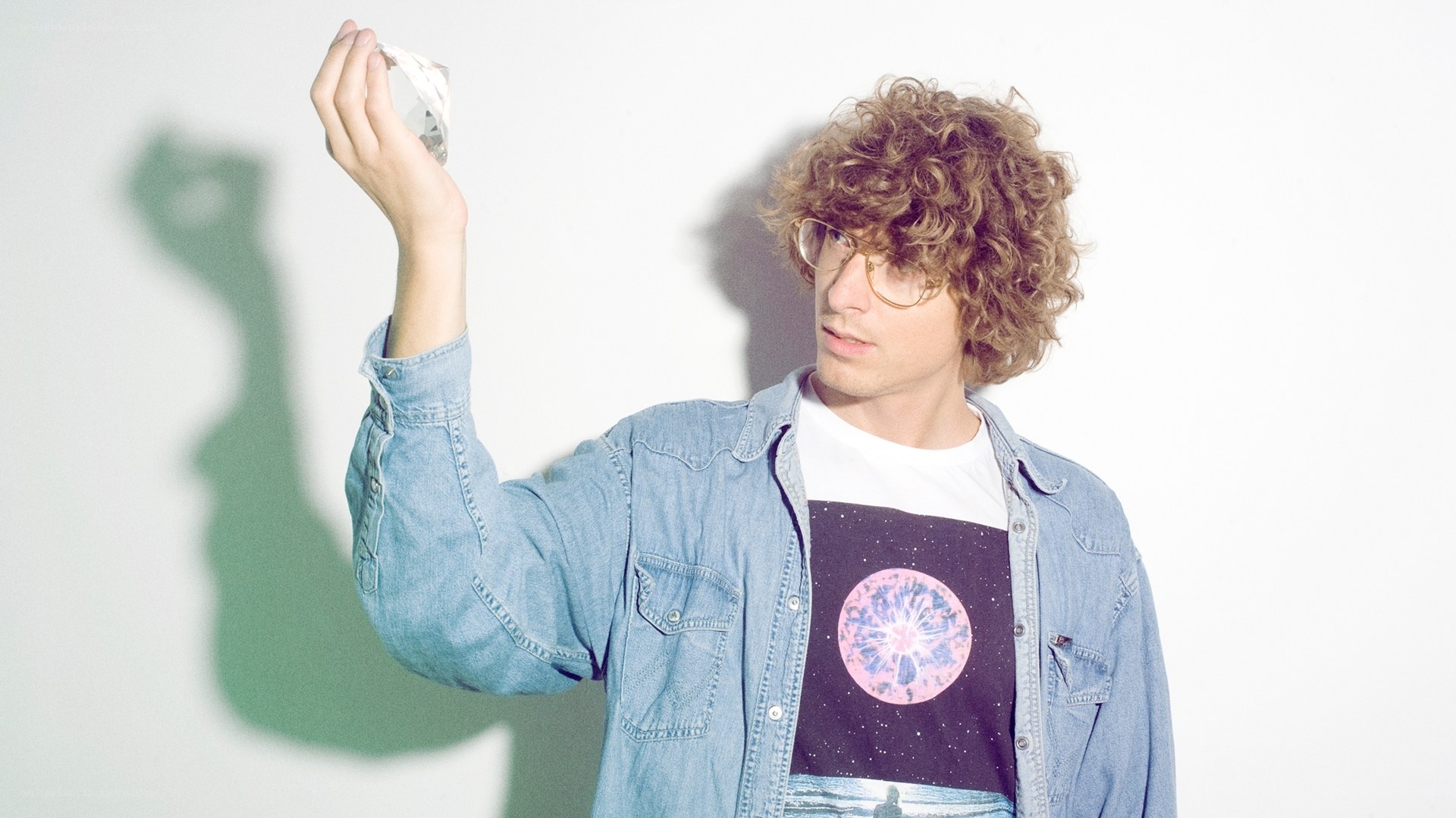 man with curly hair holding crystal