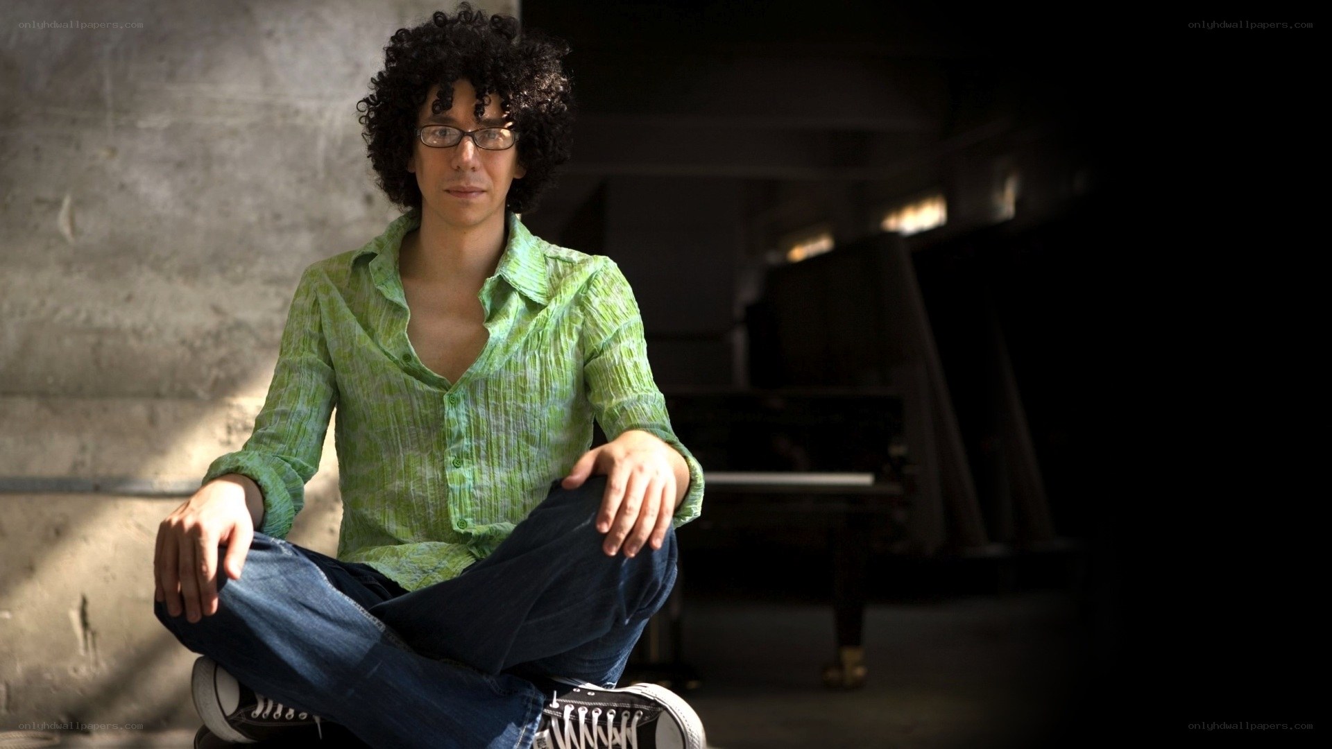 man with curly hair sitting on floor