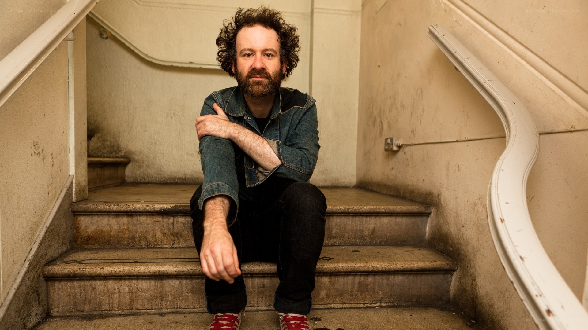 man with curly hair sitting on stairs