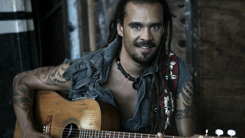 man with dreadlocks holding guitar