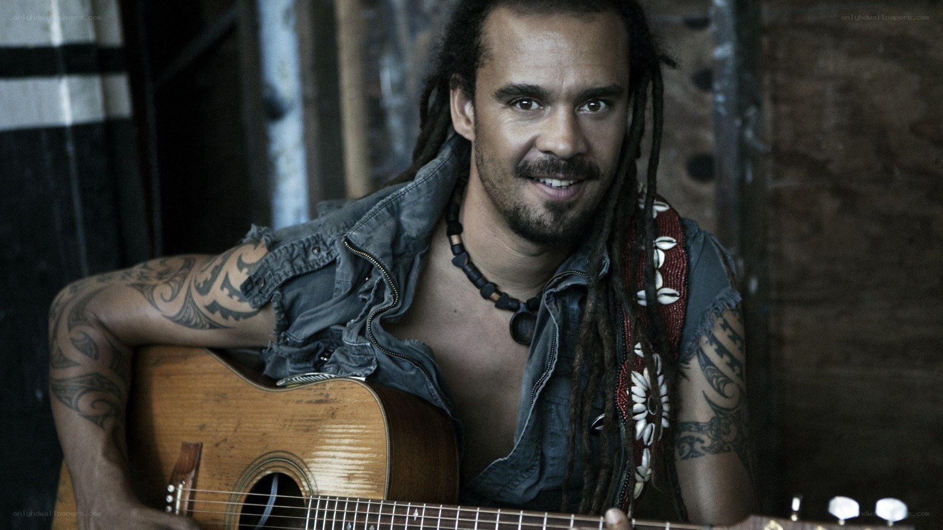 man with dreadlocks holding guitar