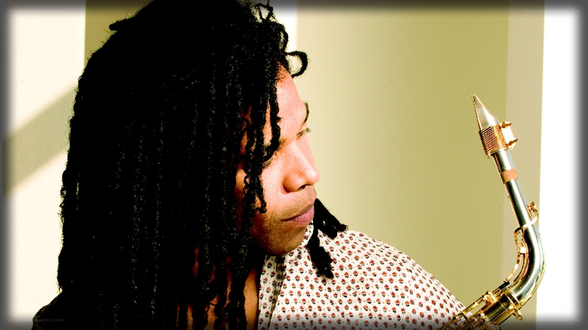 man with dreadlocks holding saxophone