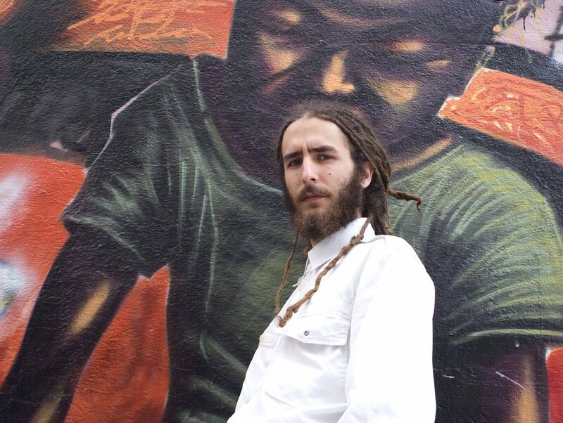 man with dreadlocks in front of mural