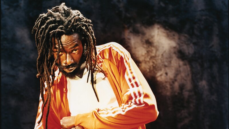 man with dreadlocks in orange jacket