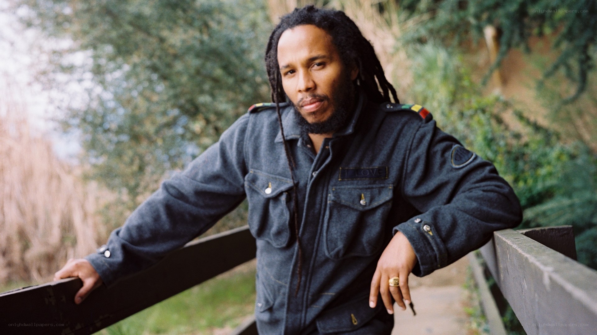 Man with dreadlocks leaning on fence
